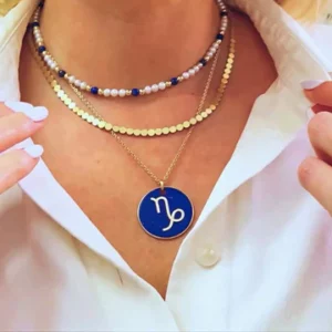 a large pendant, blue background, gold frame with zodiac sign on it in gold.